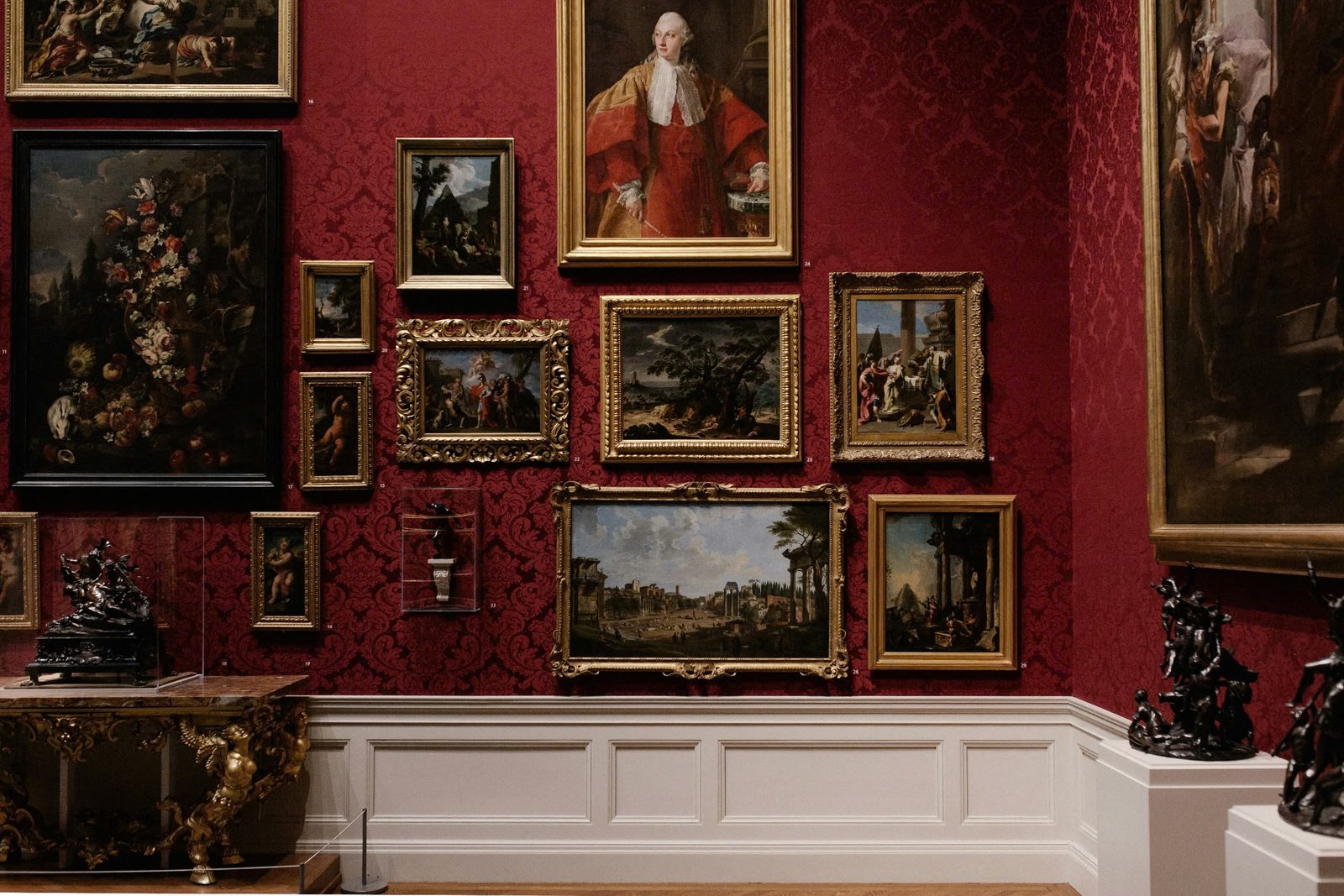 Studio wall of hand-painted oil reproductions arranged in a classical gallery setting